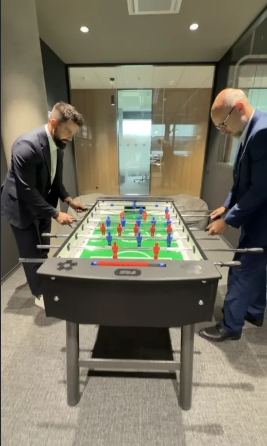 Dva kolegové z Investhy u stolního fotbálku v zasedací části kanceláře